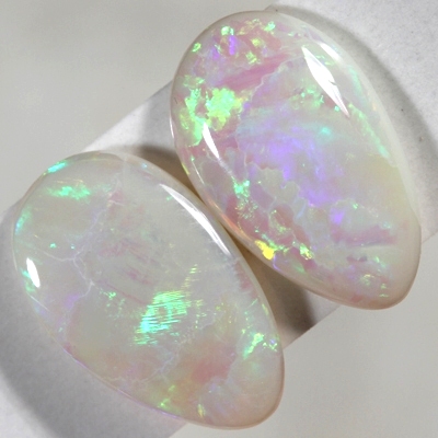 SOLID SEMI BLACK OPALS Matching pair. bright green and orange rolling flashes over a hue of purple